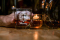 Glass of whiskey with 'Henry' branding held by a hand on a wooden surface.